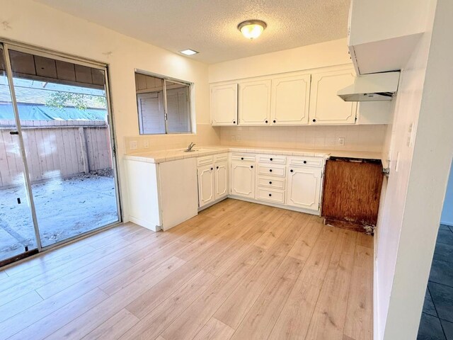 kitchen featuring sink, extractor fan, white cabinetry, and light hardwood / wood-style flooring