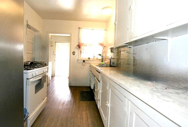 kitchen with white range with gas cooktop, dark wood-type flooring, stainless steel fridge, white cabinets, and tasteful backsplash