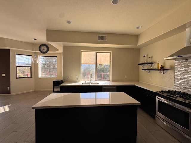 kitchen with a kitchen island, decorative light fixtures, plenty of natural light, and stainless steel gas range