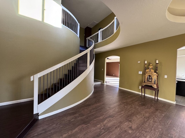 stairway featuring a towering ceiling and wood-type flooring