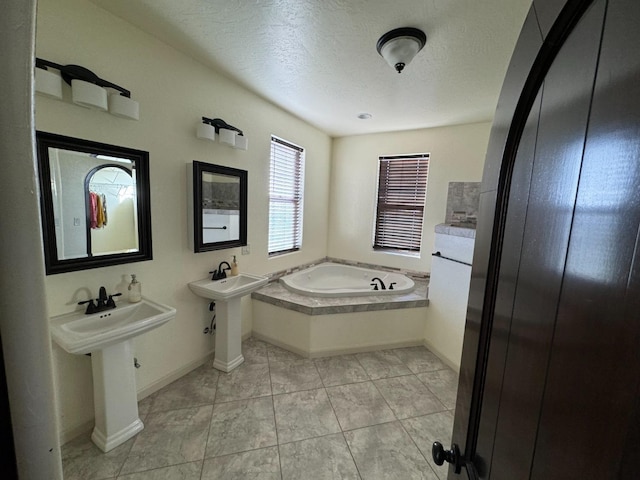 bathroom featuring tile patterned flooring, double sink, a textured ceiling, and a tub to relax in