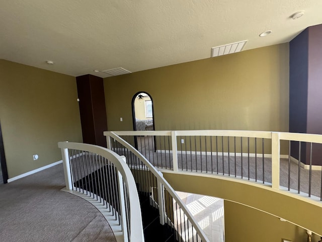 staircase with carpet floors and a textured ceiling