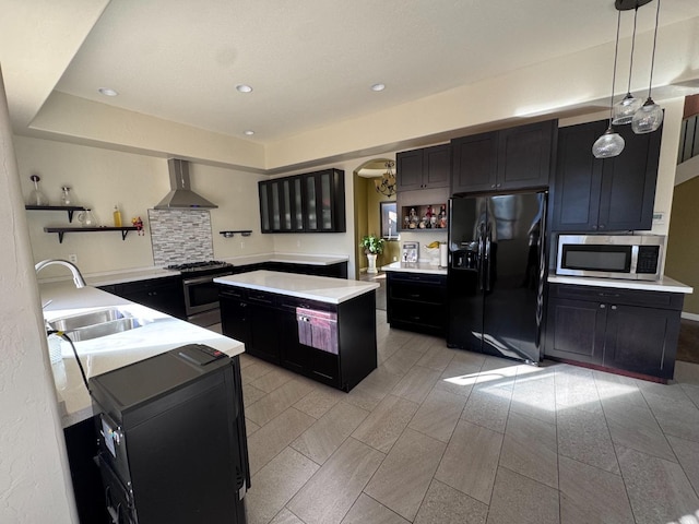 kitchen with sink, hanging light fixtures, wall chimney range hood, a chandelier, and appliances with stainless steel finishes