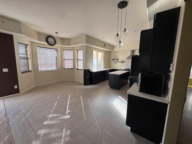 kitchen with sink, black refrigerator, pendant lighting, and a center island