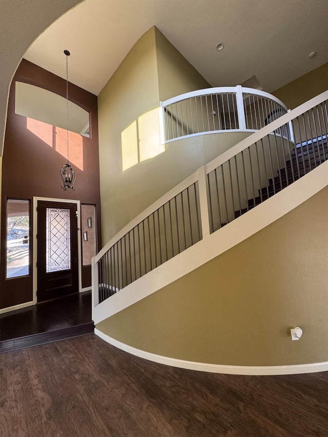 foyer entrance with a notable chandelier, hardwood / wood-style floors, and high vaulted ceiling