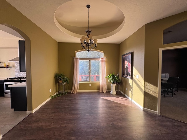 interior space with an inviting chandelier, a tray ceiling, and dark hardwood / wood-style floors