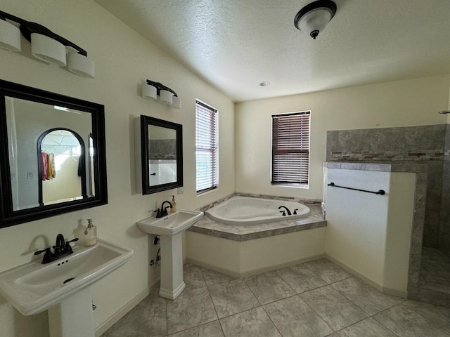 bathroom with a textured ceiling, tile patterned flooring, dual sinks, and a bathing tub