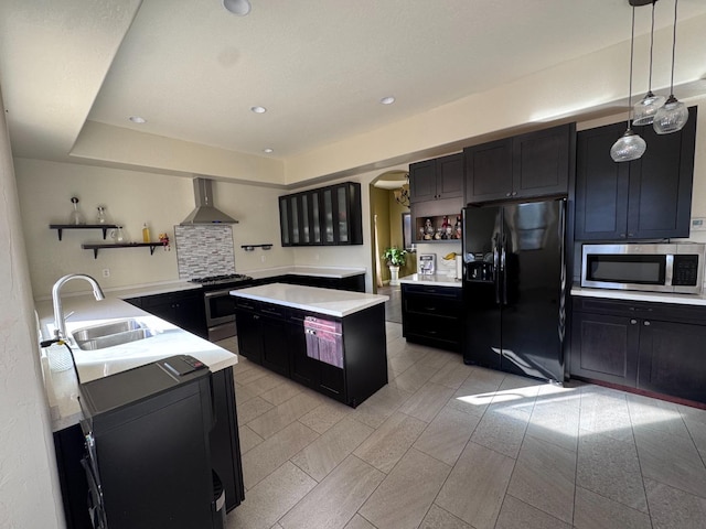 kitchen with stainless steel appliances, wall chimney exhaust hood, sink, decorative light fixtures, and backsplash