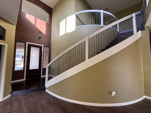 foyer entrance with a towering ceiling, wood-type flooring, and an inviting chandelier