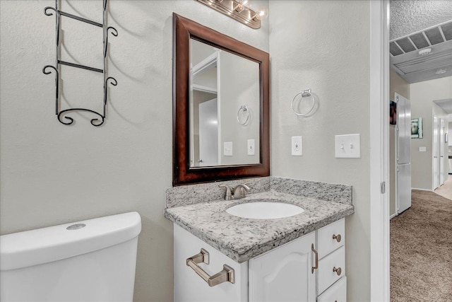 bathroom featuring toilet, vanity, and a textured ceiling