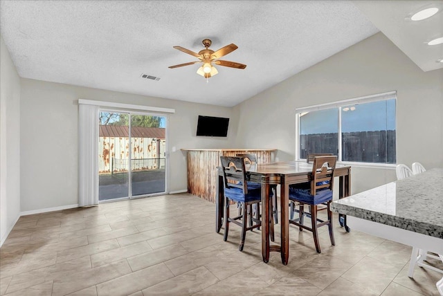 dining room with a textured ceiling, ceiling fan, and vaulted ceiling