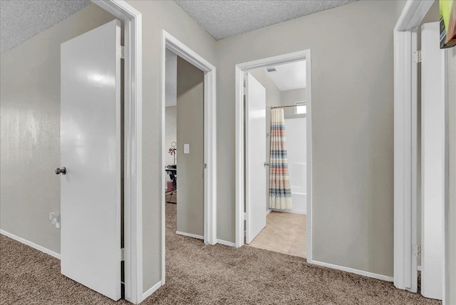 corridor featuring a textured ceiling and light colored carpet