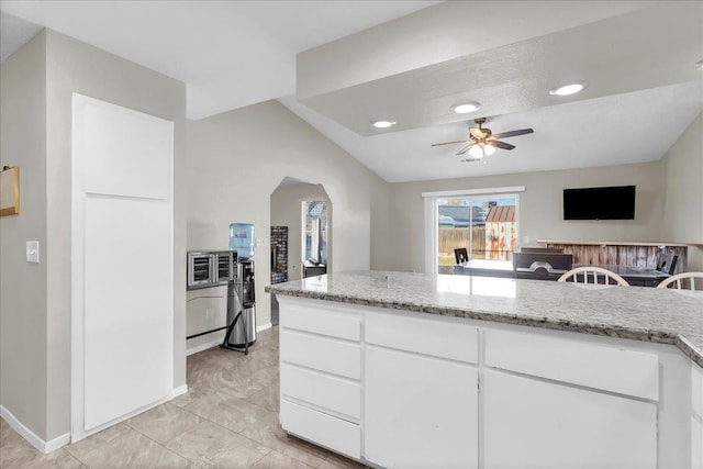 kitchen featuring lofted ceiling, light stone countertops, ceiling fan, and white cabinetry