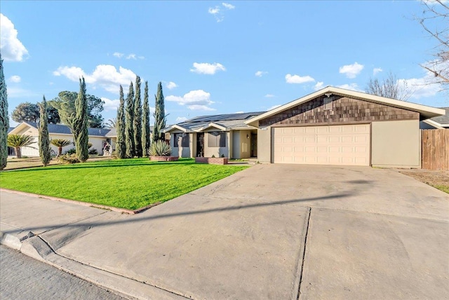 ranch-style home with solar panels, a front yard, and a garage