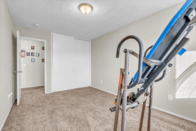 exercise room with light colored carpet and a textured ceiling