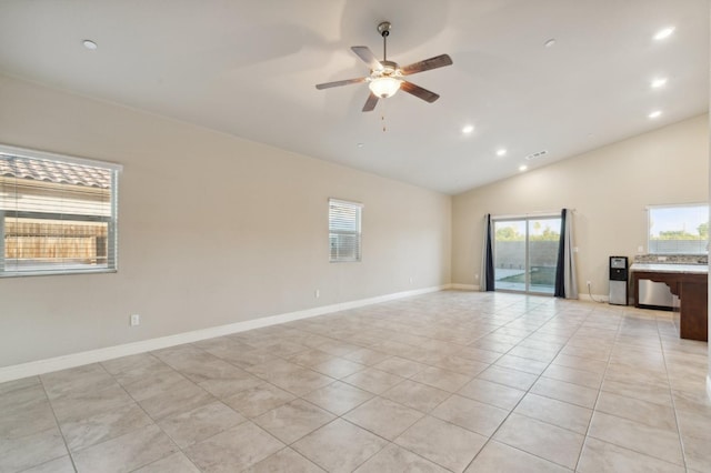 empty room with ceiling fan, vaulted ceiling, a wealth of natural light, and light tile patterned floors