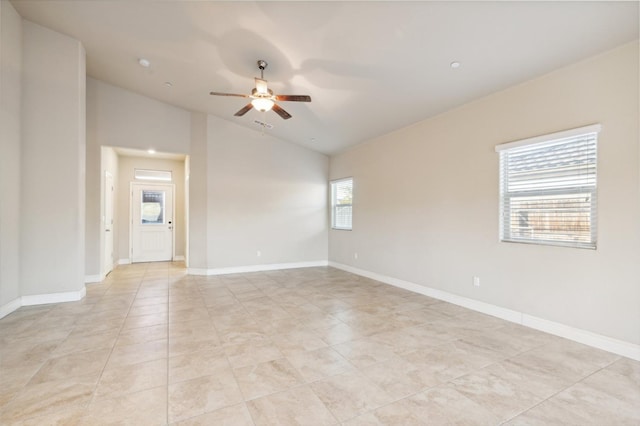 empty room featuring lofted ceiling, ceiling fan, light tile patterned floors, and plenty of natural light