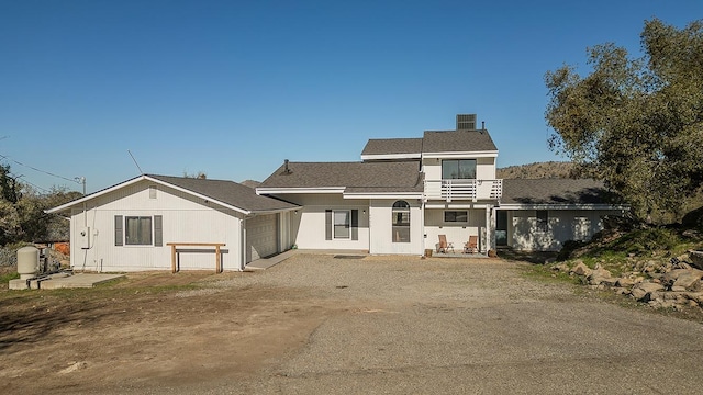 back of property featuring a garage, driveway, and a balcony