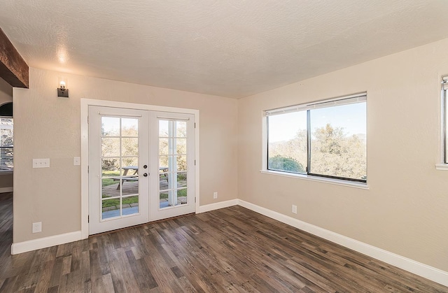 spare room featuring a textured ceiling, french doors, dark wood-style flooring, and baseboards