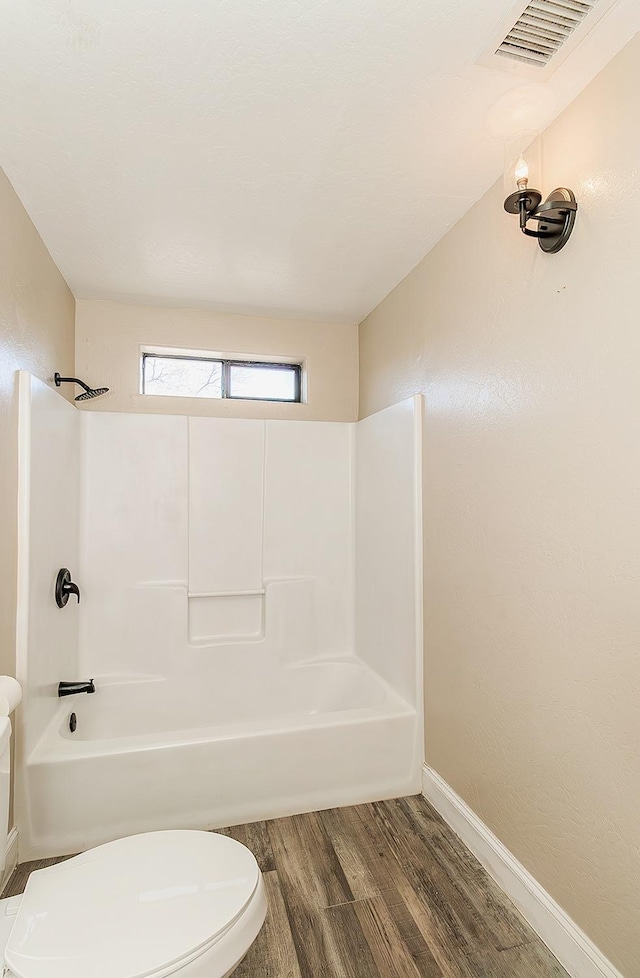 full bath featuring toilet, wood finished floors, visible vents, baseboards, and tub / shower combination