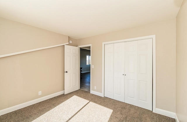 unfurnished bedroom featuring carpet floors, a closet, and baseboards