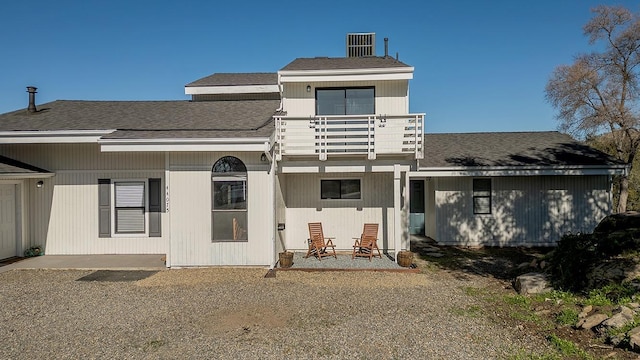 rear view of property featuring roof with shingles and a balcony