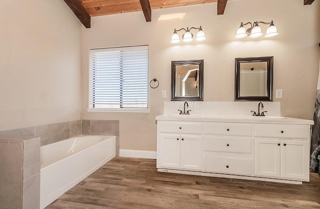 full bathroom featuring a garden tub, wood finished floors, beamed ceiling, and a sink