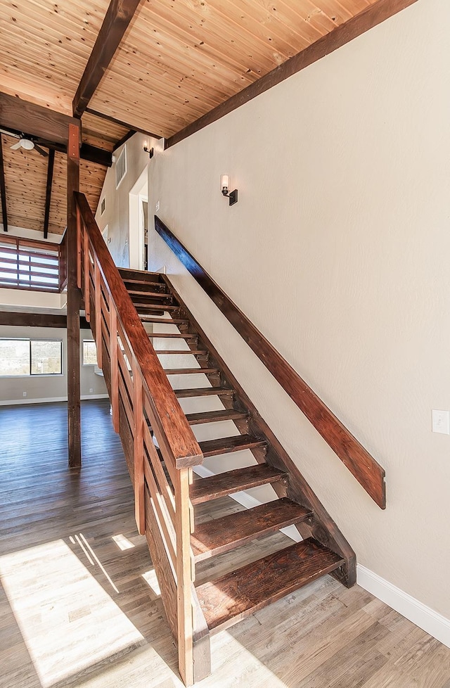 stairs with wood finished floors, a ceiling fan, wood ceiling, baseboards, and beam ceiling