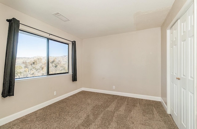 carpeted empty room featuring visible vents and baseboards