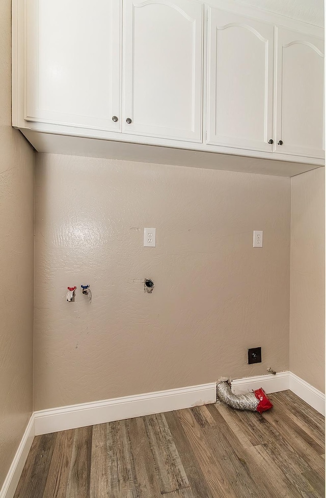 washroom featuring gas dryer hookup, wood finished floors, cabinet space, and baseboards