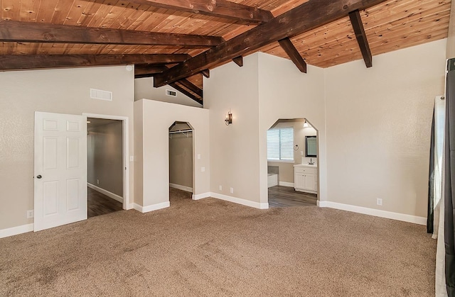 unfurnished bedroom featuring lofted ceiling with beams, arched walkways, wood ceiling, baseboards, and carpet