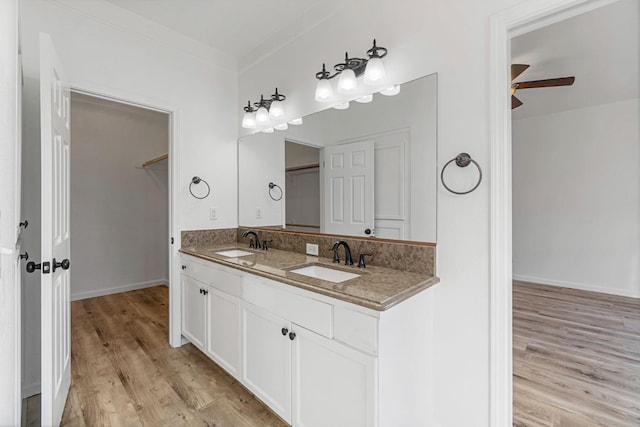 bathroom featuring ceiling fan, wood-type flooring, vanity, and crown molding