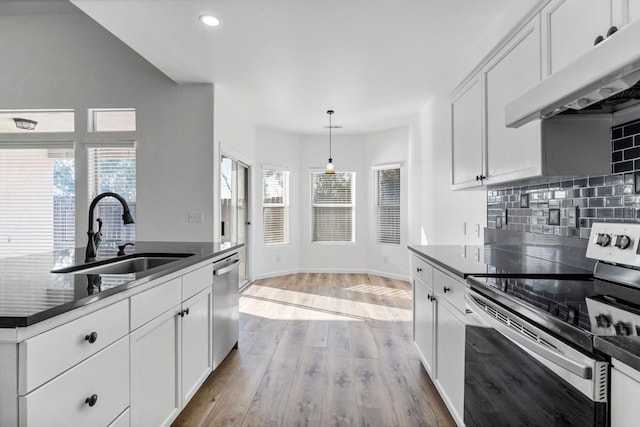 kitchen featuring pendant lighting, white cabinets, stainless steel appliances, sink, and light hardwood / wood-style flooring