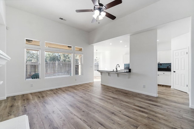 unfurnished living room with ceiling fan, light hardwood / wood-style floors, and sink