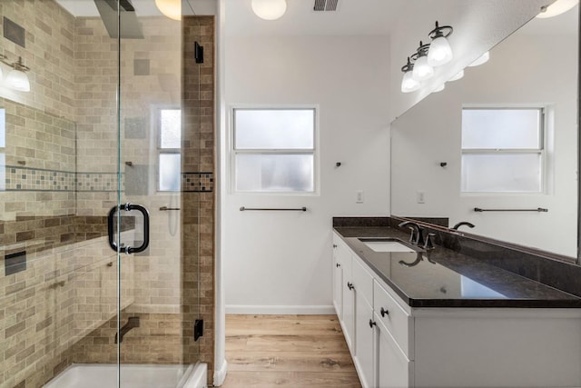 bathroom with wood-type flooring, walk in shower, and vanity