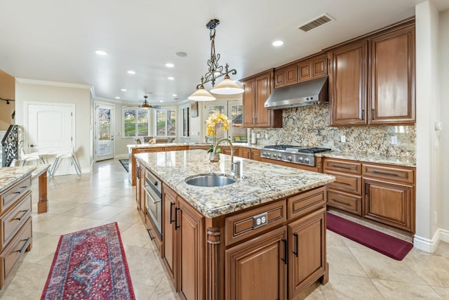 kitchen featuring an island with sink, ventilation hood, ceiling fan, stainless steel gas cooktop, and sink