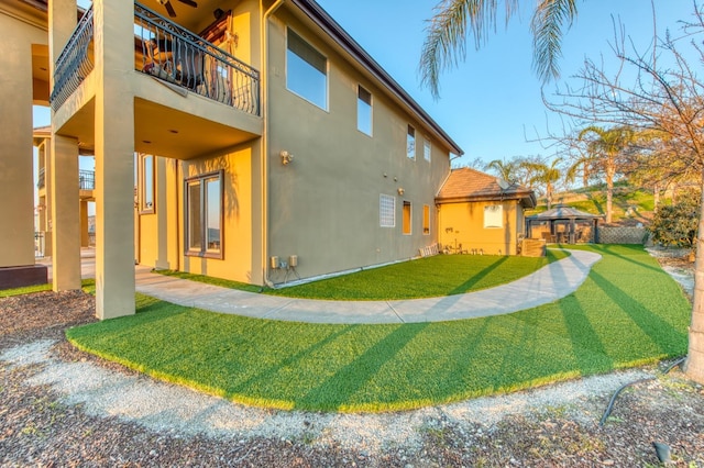 rear view of property featuring a lawn, a gazebo, and a balcony