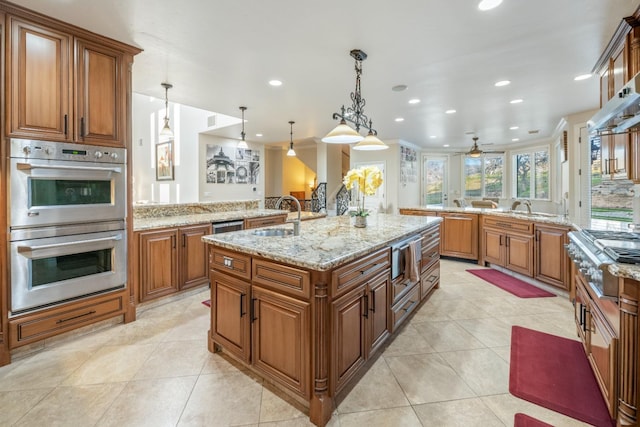 kitchen with pendant lighting, stainless steel appliances, sink, ceiling fan, and a center island with sink