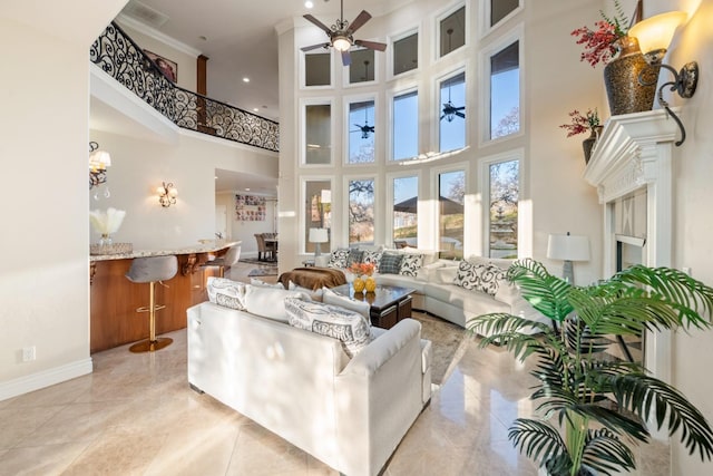 living room featuring ceiling fan, a high ceiling, and ornamental molding