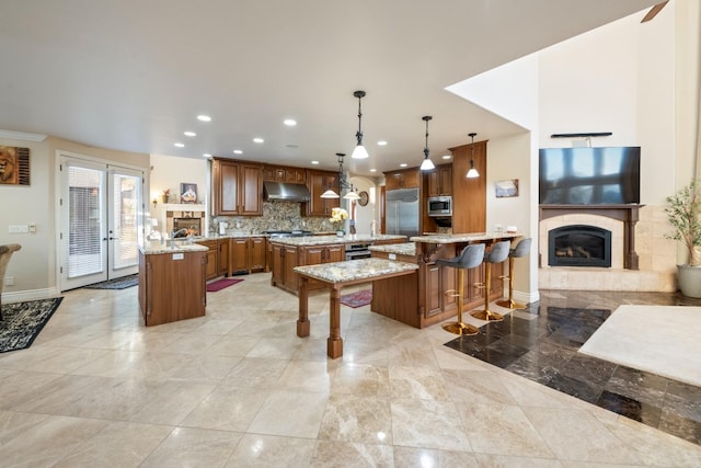 kitchen featuring a spacious island, decorative light fixtures, built in appliances, a kitchen breakfast bar, and kitchen peninsula