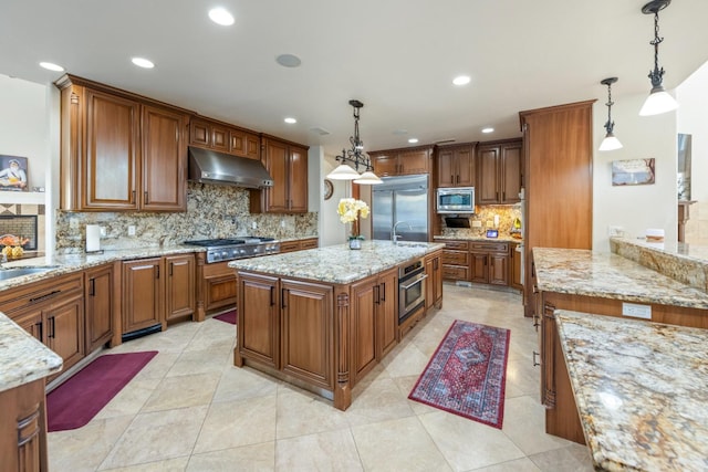 kitchen featuring decorative backsplash, pendant lighting, a kitchen island, and built in appliances