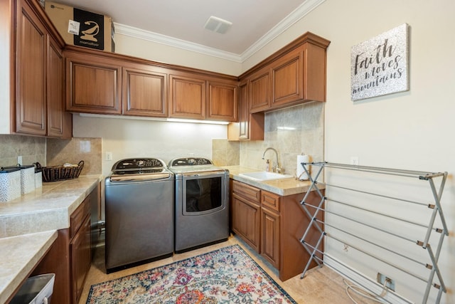 laundry room featuring light tile patterned floors, separate washer and dryer, cabinets, crown molding, and sink