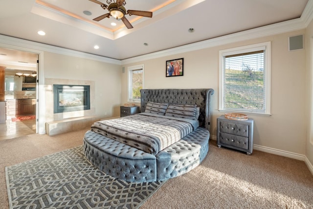 carpeted bedroom featuring ceiling fan, a tray ceiling, and ornamental molding