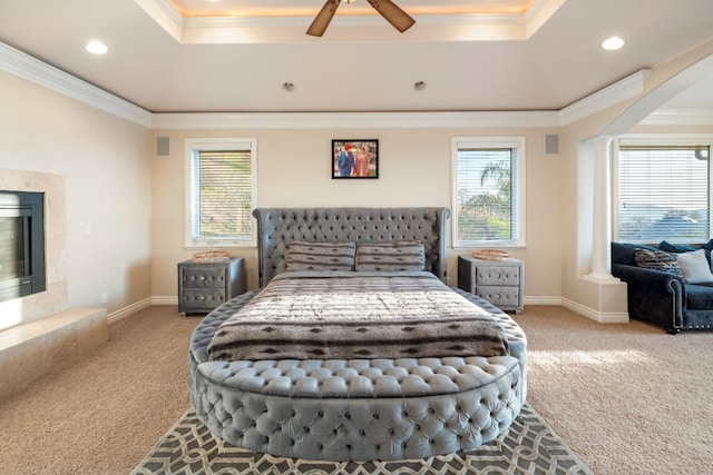 carpeted bedroom with ceiling fan, a tray ceiling, and ornamental molding