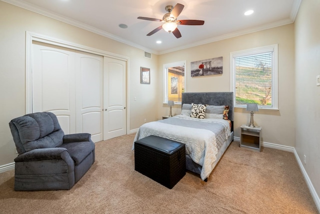 carpeted bedroom with ceiling fan, a closet, and crown molding