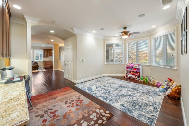 rec room with ceiling fan, dark hardwood / wood-style flooring, and crown molding