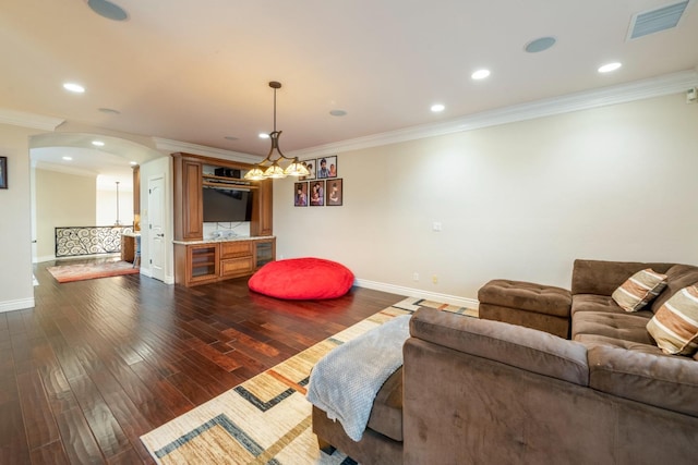 living room featuring dark hardwood / wood-style flooring, crown molding, and a chandelier