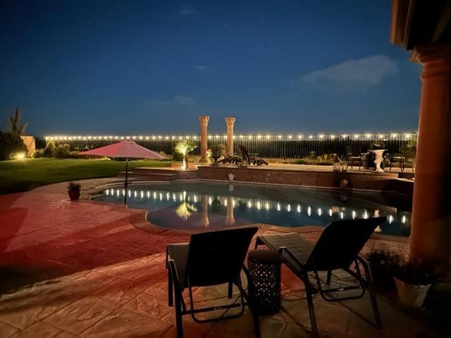 pool at twilight featuring a patio area