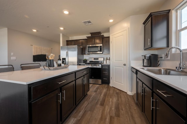 kitchen featuring appliances with stainless steel finishes, dark hardwood / wood-style floors, sink, a kitchen breakfast bar, and a center island