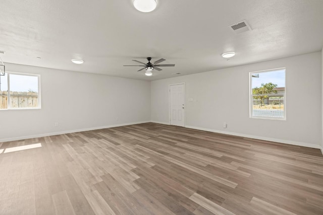 empty room with ceiling fan, wood-type flooring, and a textured ceiling